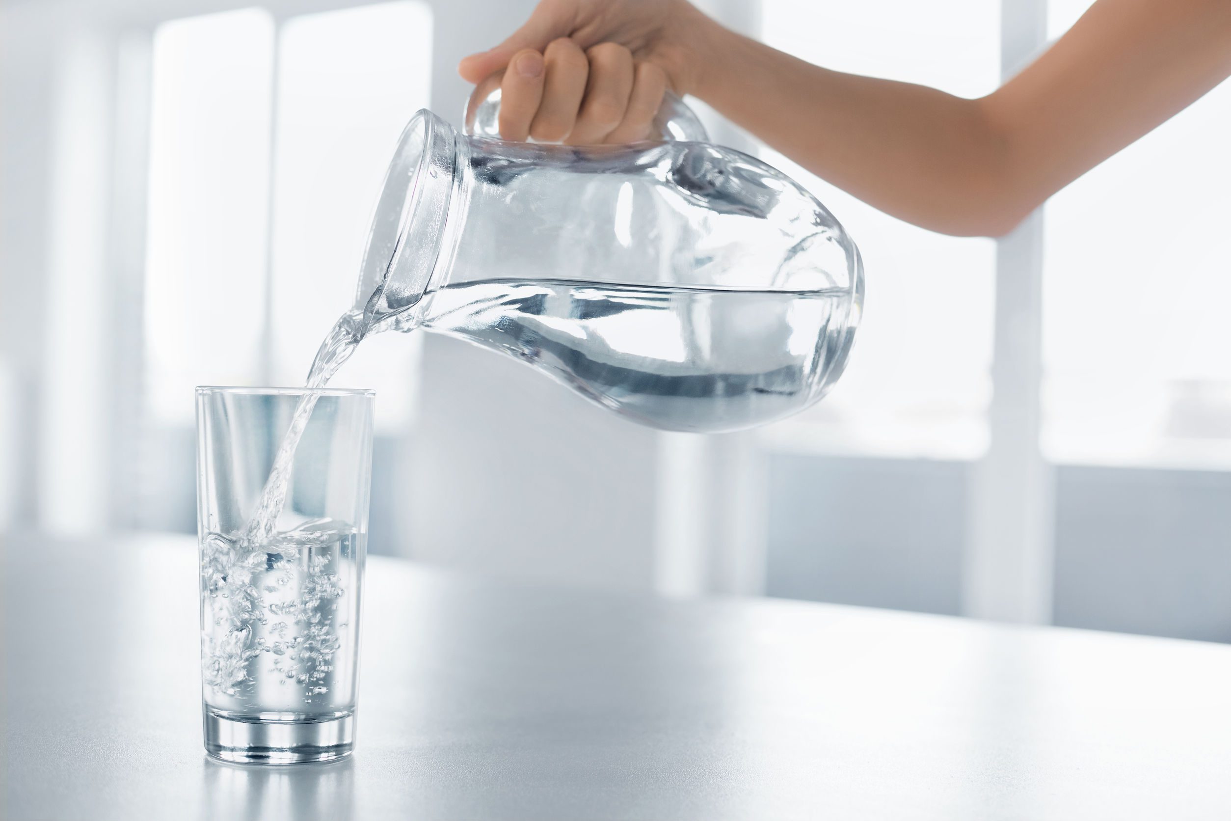 47894681 - drink water. woman's hand pouring fresh pure water from pitcher into a glass. health and diet concept. healthy lifestyle. healthcare and beauty. hydratation.